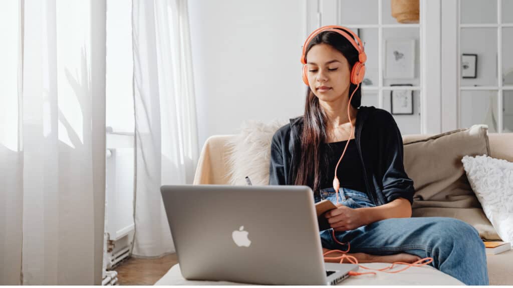 Student with headphones on studying at a laptop.