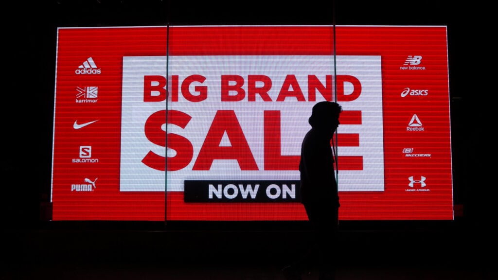 Man walking by a Big Brand Sale sign.