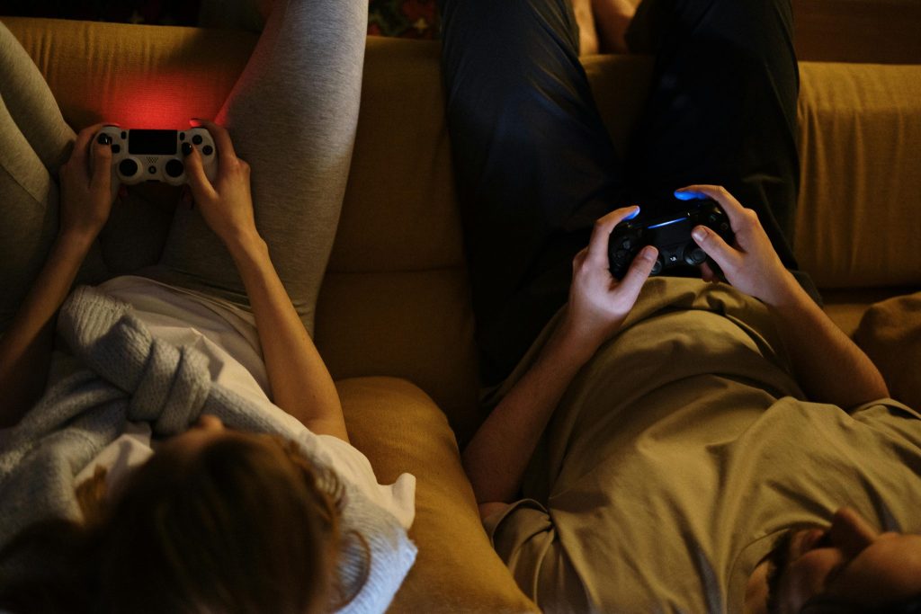People sat on sofa playing PS4 console